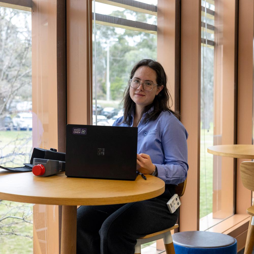 Sophie sitting at a table with ASNO laptop